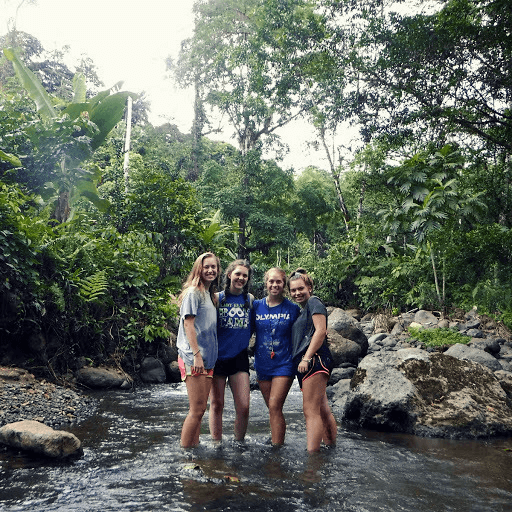 Four girls stood in a stream with ankle high water