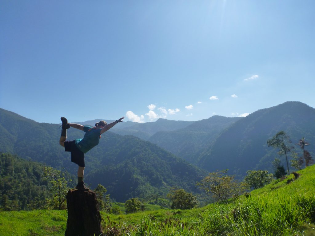 A girl doing a yoga pose on a log in the mountains