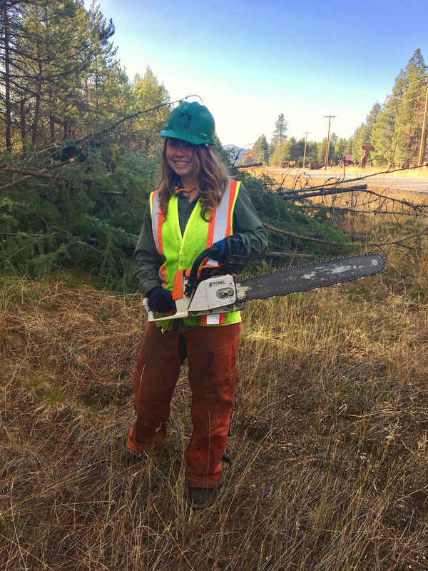 Women wearing protective equipment holding a chainsaw