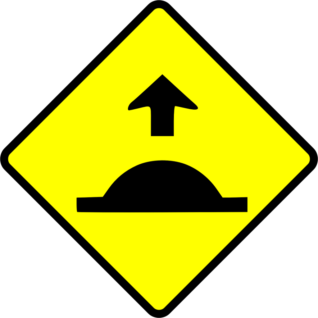 A yellow and black speed bump sign