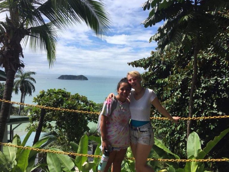 Two girls hugging at Manuel Antonio with the sea in the background