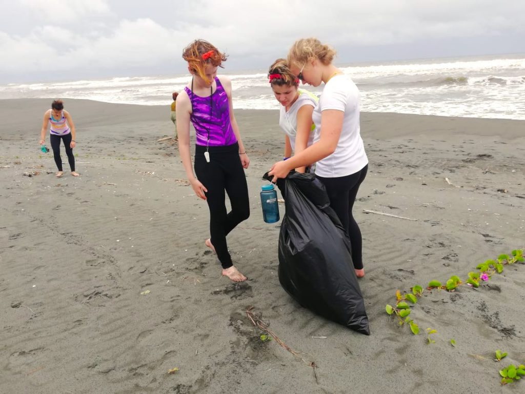 Girl scouts picking up trash on the beach