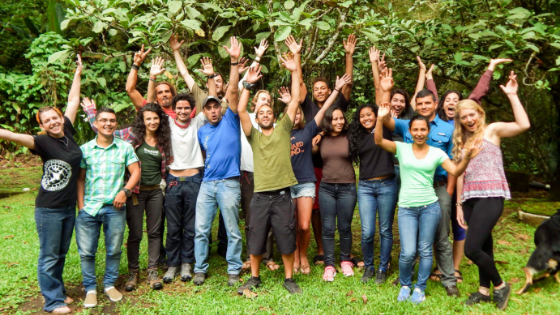A group of Outward Bound Costa Rica instructors with their hands raised in the air